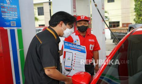 Communication and Relations PT Pertamina Patra Niaga Regional Sulawesi, Muhammad Iqbal Hidayatulloh (kiri) mengenalkan tata cara daftar konsumen BBM bersubsidi kepada pengendara mobil di SPBU Tinaloga, Kota Gorontalo, Gorontalo, Kamis (28/7/2022). PT Pertamina Patra Niaga Regional Sulawesi melakukan sosialisasi Program Subsidi Tepat dan penggunaan aplikasi My Pertamina kepada pengguna kendaraan mobil dalam upaya mewujudkan penyaluran BBM subsidi agar lebih tepat sasaran. 