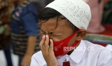  Seorang siswa sekolah dasar bereaksi ketika petugas kesehatan menyuntikkan suntikan vaksin COVID-19 selama perjalanan vaksinasi untuk anak-anak berusia antara enam hingga 11 tahun, di Banda Aceh, Indonesia, 18 Januari 2022. Sebagian keluhan yang dirasakan setelah vaksinasi Covid-19 timbul dipicu oleh sugesti.