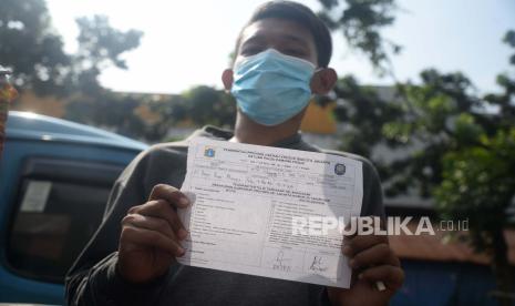 Warga menunjukan terguran tertulis usai diberikan sanksi menyapu sampah akibat melanggar Pembatasan Sosial Berskala Besar (PSBB) karena tidak menggunakan masker di tempat umum di Kawasan Pasar Minggu, Jakarta, Rabu (13/5). Sanksi bagi pelanggar PSSB ini mulai diberlakukan, adapun pengenaan sanksi kepada pelanggar mulai dari sanksi sosial hingga denda