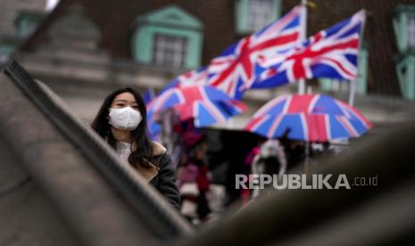  Seorang wanita mengenakan masker saat melewati toko suvenir di London, Selasa, 21 Desember 2021. Dengan cakupan vaksinasi 70 persen, Inggris mendapati jumlah pasien Covid-19 tidak sebanyak tahun lalu dan gejalanya lebih ringan dari sebelumnya.