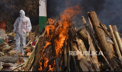 Seorang anggota keluarga, mengenakan Alat Pelindung Diri (APD), melakukan upacara terakhir untuk korban COVID-19 di tempat kremasi di New Delhi, India,  Kamis (29/4). Delhi melaporkan 25.986 kasus baru, 368 kematian dalam 24 jam terakhir dan terus berlanjut. berjuang dengan suplai oksigen.