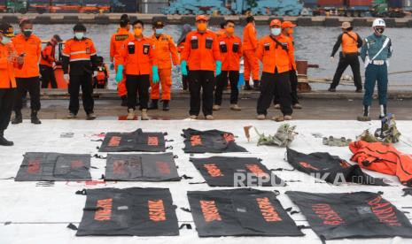 Anggota Badan Pencarian dan Penyelamatan Nasional (BASARNAS) berdiri di depan kantong mayat yang ditemukan dari lokasi kecelakaan di perairan Jakarta di pelabuhan Tanjung Priok di Jakarta, Indonesia, 17 Januari 2021. Penerbangan Sriwijaya Air SJ182 jatuh ke laut di lepas pantai Jakarta pantai pada 09 Januari 2021 tak lama setelah lepas landas dari Bandara Internasional Jakarta saat dalam perjalanan ke Pontianak di provinsi Kalimantan Barat