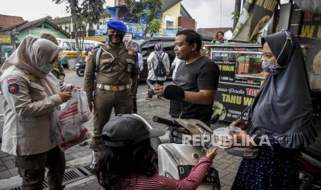 Petugas Satpol PP Kota Bandung memberikan masker ke pengendara saat operasi gabungan patroli pengawasan dan penegakan disiplin (Gakplin) protokol kesehatan Covid-19 di Antapani Kidul, Kecamatan Antapani, Kota Bandung, Rabu (10/2). Operasi tersebut digelar dalam rangka pemberlakuan pembatasan kegiatan masyarakat (PPKM) skala mikro guna menertibkan masyarakat agar lebih disiplin dalam menerapkan protokol kesehatan Covid-19 serta mencegah penyebaran Covid-19 di tingkat desa atau kelurahan. 