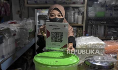 Pedagang menunjukkan kode batang QRIS (Quick Response Code Indonesian Standard) di salah satu kios di Pasar Kosambi, Kota Bandung, Jawa Barat, Senin (10/7/2023). Bank Indonesia memberlakukan biaya layanan QRIS bagi Penyedia Jasa Pembayaran (PJP) sebesar 0,3 persen dari yang sebelumnya sebesar 0 persen atau gratis. Dalam aturan yang berlaku sejak 1 Juli tersebut, pedagang tidak boleh membebankan balik ke konsumen atau pembeli.