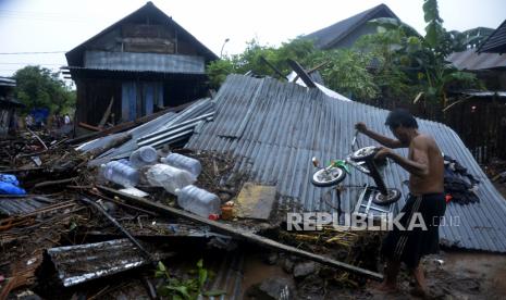 Seorang warga mengangkat sisa barangnya didekat rumah yang rusak terseret arus banjir bandang di Kecamatan Bissappu, Kabupaten Bantaeng, Sulawesi Selatan, Sabtu (13/6/2020). Banjir bandang yang terjadi akibat jebolnya tanggul bendungan Balangsikuyu yang tidak mampu menampung tingginya curah hujan tersebut mengakibatkan puluhan rumah rusak berat dan hilang diterjang banjir yang disertai dengan material batu dan lumpur