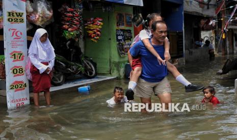 Orang tua menggendong anaknya saat melintasi banjir rob di kawasan Muara Angke, Jakarta Utara, Selasa (19/11/2024). Banjir setinggi sekitar 30-60 centimeter tersebut terjadi akibat pasang air laut yang melanda beberapa kawasan di pesisir Jakarta Utara. Warga menuturkan banjir tersebut menggenangi pemukiman kawasan pesisir sudah memasuki hari kelima. Sementara menurut BPBD DKI Jakarta fenomena pasang maksimum air laut disebabkan oleh fase bulan baru yang berpotensi banjir rob hingga 21 November mendatang.