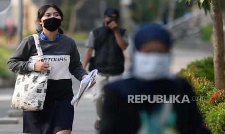 Satuan Polisi Pamong Praja Jakarta Barat mulai memberlakukan sanksi sosial bagi pelanggar pembatasan sosial berskala besar (PSBB) dengan menyapu trotoar. [Foto ilustrasi sejumlah pekerja berjalan mengenakan masker].