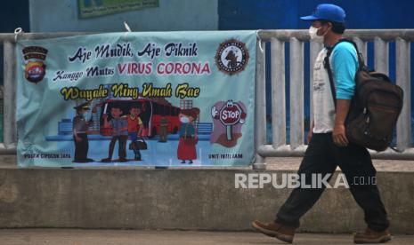 Warga melintas dekat spanduk ajakan tidak mudik menjelang puasa dan lebaran di Terminal Bis Kota Serang. Mahasiswa yang mudik terindikasi Covid-19 dan ditolak masuk kampung oleh warga. Ilustrasi.