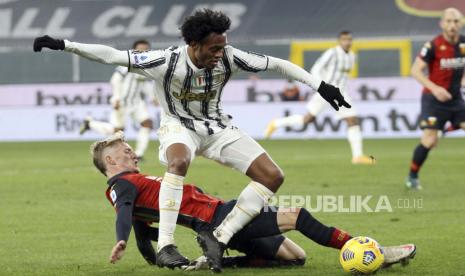 Juan Cuadrado dari Juventus, atas, dan Nicolo Rovella dari Genoa beraksi selama pertandingan sepak bola Serie A Italia antara Genoa dan Juventus, di stadion Luigi Ferraris di Genoa, Italia, Minggu, 13 Desember 2020. 