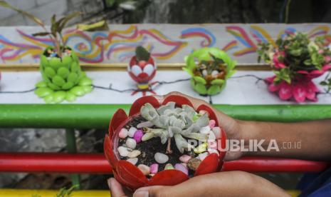 Warga memperlihatkan pot tanaman yang dibuat dari limbah plastik di Jalan Dr. Saharjo, Tebet, Jakarta, Senin (7/3/2022). Pot tanaman yang dibuat dengan memanfaatkan limbah plastik rumah tangga seperti botol air mineral dan galon tidak terpakai tersebut untuk menata lingkungan agar terlihat lebih indah. 