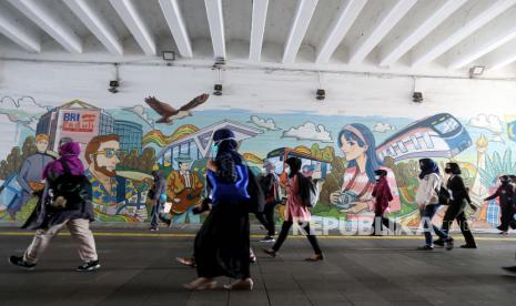  Penumpang berjalan melewati mural di dekat stasiun kereta api selama pembatasan Covid-19 di Jakarta, Selasa (31/8). Pemerintah  memperpanjang periode pemberlakuan keadaan darurat pembatasan mobilitas publik dari 31 Agustus hingga 06 September 2021, dengan nomor Relaksasi untuk kegiatan masyarakat, seperti melakukan uji coba pembukaan kembali beberapa tempat umum, dengan syarat pengunjung membawa surat keterangan vaksinasi COVID-19.