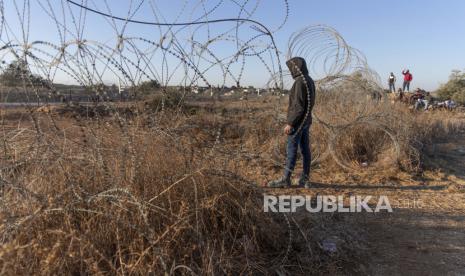  Warga Palestina berkumpul di bagian pembatas pemisah Israel, sementara mereka menunggu tentara Israel mengizinkan mereka melintasi pagar, di desa Nilin, Tepi Barat, barat Ramallah,  Ahad ( 7/11//2021). Hampir dua dekade setelah Israel memicu kontroversi di seluruh dunia dengan membangun penghalang selama pemberontakan Palestina, itu telah menjadi fitur yang tampaknya permanen dari lanskap - bahkan ketika Israel mendorong warganya untuk menetap di kedua sisi.