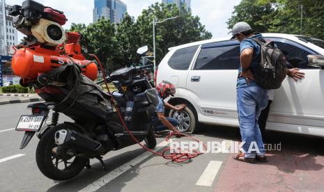 Tukang tambal ban menambahkan angin ban mobil yang dikempiskan petugas karena melanggar peraturan parkir di Jalan Medan Merdeka Selatan, kawasan Monumen Nasional (Monas), Jakarta, Ahad (29/12/2024). Petugas Dishub DKI Jakarta mengempiskan puluhan ban kendaraan yang kedapatan melanggar aturan karena parkir di bahu Jalan Medan Merdeka Selatan sesuai dengan Peraturan Daerah Provinsi DKI Jakarta Nomor 5 tahun 2012. 