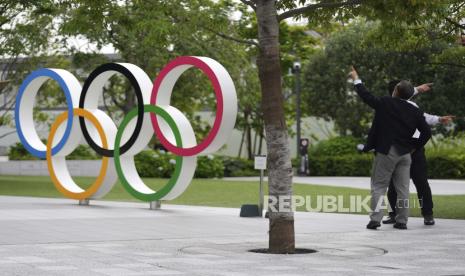 Pria memberi isyarat di dekat Cincin Olimpiade Rabu, 2 Juni 2021, di Tokyo.