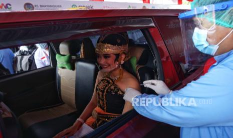 Petugas kesehatan menyuntikkan vaksin Covid-19 kepada peserta saat vaksinasi sistem drive thru di Candi Prambanan, Kabupaten Sleman, D.I Yogyakarta, Senin (5/4/2021). 