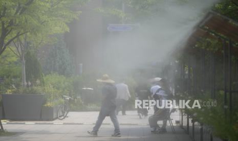 Orang-orang berkumpul di bawah kabut air untuk mendinginkan diri di pusat kota Seoul, Korea Selatan, Jumat, 14 Juni 2024. Badan Meteorologi Korea Selatan telah mengeluarkan peringatan gelombang panas untuk beberapa bagian semenanjung Korea.