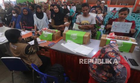 Warga mengambil bantuan pangan berupa telur dan daging ayam untuk keluarga rawan stunting di Kantor Pos, Kota Kediri, Jawa Timur, Jumat (27/9/2024). Badan Pangan Nasional (Bapanas) memeberikan bantuan pangan berupa 10 butir telur ayam dan 1 kg daging ayam tersebut didistribusikan melalui pemerintah daerah setempat kepada 2.155 keluarga penerima manfaat sebagai upaya mendorong peningkatan kesehatan dan kesejahteraan keluarga rawan stunting. 