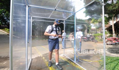 Seorang siswa baru melewati bilik sterilisasi saat akan mengikuti Masa Pengenalan Lingkungan Sekolah (MPLS) di SMK Negeri 2 Salatiga, Jawa Tengah, Senin (13/7/2020). Sebanyak 642 siswa baru mengikuti MPLS secara langsung dengan dua kelas program keahlian yang dilakukan bergilir dalam satu hari dengan tetap menerapkan protokol kesehatan COVID-19. 