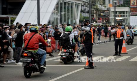 Petugas Dinas Perhubungan (Dishub) mengatur lalu lintas di area zebra cross yang dijadikan lokasi peragaan busana Citayam Fashion Week di kawasan Dukuh Atas, Jakarta, Rabu (27/7/2022). Sejumlah petugas gabungan dari Dishub dan Satpol PP melakukan penjagaan dan normalisasi fungsi zebra cross untuk penyeberangan serta perlintasan kendaraan motordan mobil. Meski demikian, kegiatan fashion show jalanan tersebut masih tetap berlangsung dengan imbauan untuk menjaga ketertiban agar tidak terjadi kemacetan. Republika/Thoudy Badai