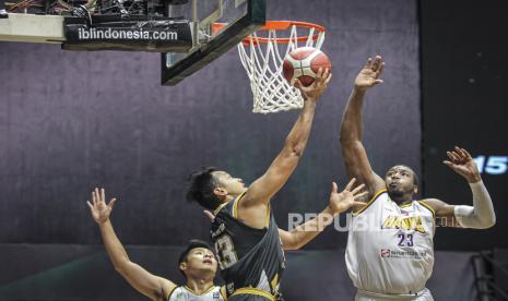 Pebasket Dewa United Surabaya Kaleb Ramot Gemilang (tengah) melakukan lay up dibayangi pebasket Tangerang Hawks Basketball Club Richard David Ross JR (kanan) pada pertandingan Seri 1 Jakarta Indonesian Basketball League (IBL) 2022 di Hall Basket GBK, Jakarta, Kamis (20/1/2022). Dewa United Surabaya menang atas Tangerang Hawks Basketball Club dengan skor 70-68. 