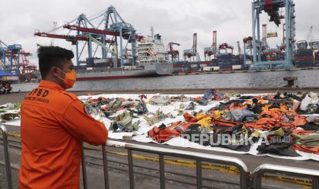 Seorang petugas penyelamat memeriksa puing-puing yang ditemukan di perairan lepas Pulau Jawa di sekitar tempat pesawat penumpang Sriwijaya Air jatuh, di Pelabuhan Tanjung Priok, Jakarta, Indonesia, Minggu, 17 Januari 2021. Penyidik ??telah mengunduh informasi dari perekam data penerbangan pesawat, yang pulih awal pekan ini.