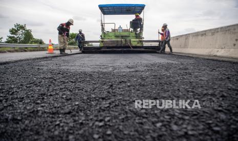 Pekerja dibantu alat berat menyelesaikan pengaspalan Jalan Tol Trans Sumatera ruas Kayu Agung-Palembang (Kapal) di Jejawi, Ogan Komering Ilir (OKI), Sumatera Selatan, Senin (3/4/2023). Menteri Keuangan (Menkeu) RI Sri Mulyani Indrawati mengatakan hasil pembangunan infrastruktur vital meningkat signifikan