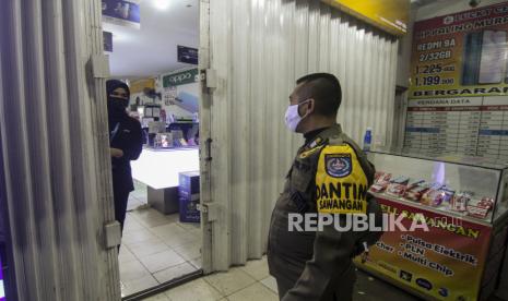 Petugas Satpol PP memberikan imbaun agar segera menutup toko saat operasi pembatasan jam operasional di Sawangan, Depok, Jawa Barat, Selasa (22/6/2021). Pemerintah Kota Depok memberlakukan pembatasan jam operasional terhadap pusat perbelanjaan, restoran, dan pertokoan hingga pukul 19.00 WIB dan aktivitas warga hingga pukul 21.00 WIB guna mencegah penyebaran COVID-19. 