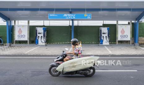  Seorang pria mengendarai skuter melewati stasiun pengisian kendaraan listrik umum yang baru dibangun. Gubernur Jatim Khofifah Indar Parawansa dorong warga untuk beralih kendaraan listrik.