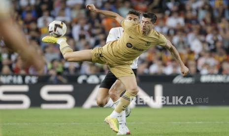 Pemain FC Barcelona Robert Lewandowski (kanan) beraksi melawan pemain Valencia CF Gabriel Paulista selama pertandingan sepak bola LaLiga Spanyol antara Valencia CF dan FC Barcelona, Ahad (30/10/2022). 