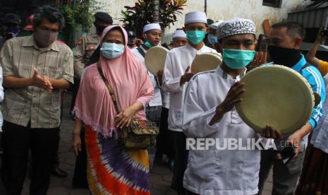 Warga menyambut pasien COVID-19 yang dinyatakan sembuh, Sukati (dua dari kiri) dan Hartoyo (kiri) dengan maukhid atau hadrah di depan rumahnya di Kiduldalem, Malang, Jawa Timur, Rabu (22/7/2020). Penyambutan tersebut sengaja dilakukan warga untuk memberi semangat sekaligus mengingatkan warga lainnya agar terus waspada terhadap penyebaran COVID-19. ANTARA FOTO/Ari Bowo Sucipto/pras.