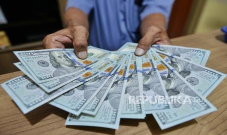 Petugas menunjukan uang dollar AS di Money Changer, Jakarta. Rupiah melemah 55,50 poin atau 0,37 persen menuju level Rp 15.205,5 per dolar AS.