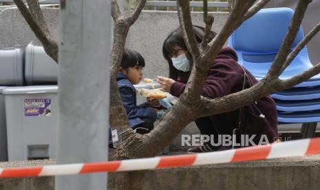  Seorang wanita memberi makan seorang anak di dekat area penampungan di luar Caritas Medical Center di Hong Kong Rabu, 16 Februari 2022. Komisi Kesehatan Nasional (NHC) Cina mengatakan Covid-19 berkontribusi pada penurunan angka kelahiran dan pernikahan di negara itu. 