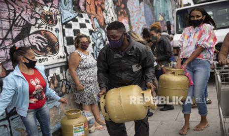 Brasil akan Beli Vaksin Covid-19 Sekali Suntik Buatan China. Orang-orang yang memakai masker di tengah pandemi COVID-19, membawa tangki gas masak yang mereka beli dari Petrobras Oil Tankers Union, bagian dari kampanye solidaritas untuk menjual bahan bakar dengan harga murah, di Rio de Janeiro, Brasil, Kamis, 29 April, 2021.