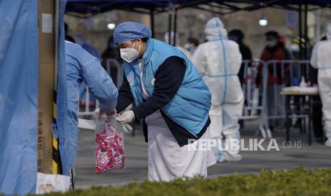 Petugas kesehatan memasukkan sampel uji COVID-19 ke dalam tas di lokasi pengujian yang disiapkan di luar Drum Tower, Rabu, 23 Maret 2022, di Beijing, China. China melaporkan total 13.287 kasus harian Covid-19 baru pada Ahad (3/4/2022) waktu setempat. 