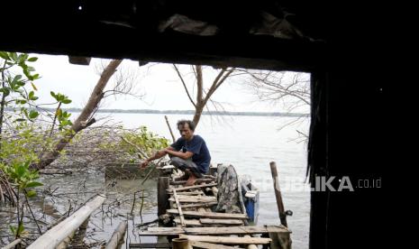  Rokhim, salah satu dari sedikit warga Desa Mondoliko yang tinggal di belakang setelah sebagian besar tetangganya pergi karena naiknya permukaan laut yang menggenangi lingkungan mereka di pantai utara Pulau Jawa, duduk di belakang rumahnya yang sekarang hampir ditelan oleh air laut di Mondoliko, Jawa Tengah, Senin (8/11/2021). Para pemimpin dunia berkumpul di Skotlandia pada KTT iklim PBB, yang dikenal sebagai COP26, untuk mendorong negara-negara meningkatkan upaya mereka untuk mengekang perubahan iklim. 