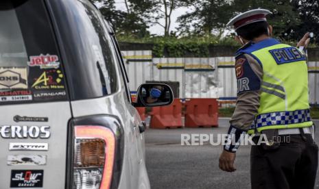 Petugas kepolisian mengarahkan kendaraan untuk memutar balik di pos pemeriksaan Pembatasan Sosial Berskala Besar (PSBB) di Gerbang Tol Cileunyi, Kabupaten Bandung, Selasa (28/4). Penindakan berupa pemeriksaan surat kendaraan, surat tugas serta mengarahkan kendaraan untuk memutar balik tersebut merupakan tidak lanjut kebijakan larangan penggunaan kendaraan umum dan kendaraan bermotor pribadi untuk mudik