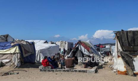 Sebuah keluarga Palestina yang mengungsi dari Rafah duduk di luar tempat penampungan mereka di Deir Al Balah, Jalur Gaza selatan, 14 Februari 2024. 