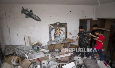 Anak-anak Palestina berjalan melewati mural yang dilukis di atas puing-puing sebuah rumah yang hancur dalam serangan Israel di Deir al-Balah, Jalur Gaza tengah, pada 8 Juni  2023.