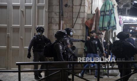 Anggota Polisi Israel mendorong mundur warga Palestina di dekat Gerbang Damaskus ke Kota Tua Yerusalem, Sabtu (24/4). Bentrokan antara polisi dan pengunjuk rasa Palestina terjadi pada malah hari di bulan suci Ramadhan. (AP Photo/Maya Alleruzzo)