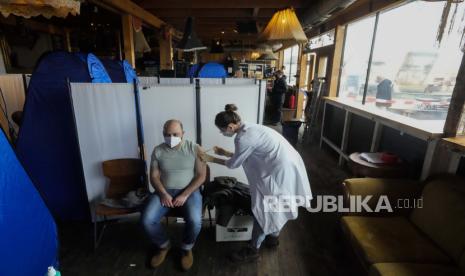  Seorang dokter menyuntikkan vaksinasi terhadap virus corona dan penyakit COVID-19 kepada seorang pria di dalam restoran dan klub malam Klunkerkranich selama kampanye vaksinasi Clubkommission yang sedang berlangsung di Berlin, Jerman, Rabu, 5 Januari 2022.