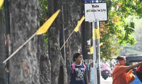 Sejumlah  warga melintas disamping bendera kuning yang dipasang di Jalan Raya Plumpang Semper, Rawabadak, Jakarta Utara, Jumat (13/9/2024). Sebanyak 200 bendera dipasang warga untuk mengenang korban kecelakaan kendaraan yang menewaskan lima orang dan tujuh korban luka pada (4/9). 