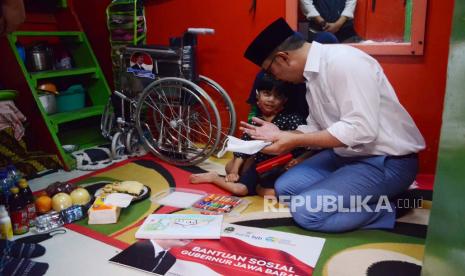 Gubernur Jawa Barat Ridwan Kamil berdoa bersama Vien Larasaty (10 tahun) penyandang disabilitas usai penyerahan bantuan sosial bersama Jabar Quick Response di Jalan Bongkaran, Kota Bandung, Senin (1/8). Dalam kesempatan itu Vien mendapat kursi roda, perlengkapan menggambar dan sejumlah bantuan lainnya.