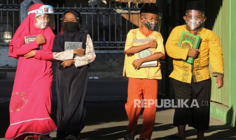 Sejumlah santri mengunakan masker dan pelindung wajah berjalan menuju lokasi kegiatan belajar membaca Al Quran,  di Diniyah Takmiliyah Awaliyah (DTA) Ummi Kulsum, Karawang, Jawa Barat, Selasa (25/8/2020). Kegiatan tersebut kembali dilaksanakan setelah terhenti selama tiga bulan akibat pandemi COVID-19 dengan menyesuaikan kondisi adaptasi kebiasaan baru melalui penerapan protokol kesehatan dan pengaturan shift belajar.