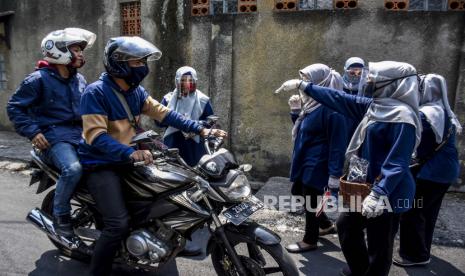 Ibu-ibu Pemberdayaan Kesejahteraan Keluarga (PKK) RW 11 Kelurahan Cikutra menghentikan pengendara motor yang melintas saat razia penggunaan masker di Jalan Sekepanjang, Cikutra, Kota Bandung, Ahad (13/9). Razia penggunaan masker tersebut guna mendisiplinkan warga untuk patuh terhadap protokol kesehatan pencegahan penyebaran Covid-19. Foto: Abdan Syakura/Republika