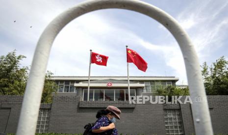 Seorang wanita yang mengenakan masker wajah berjalan oleh gedung kantor Daerah Administratif Khusus Hong Kong di Beijing, Selasa, 30 Juni 2020. Media Hong Kong melaporkan bahwa Tiongkok telah menyetujui undang-undang yang kontroversial yang akan memungkinkan pihak berwenang untuk menindak subversif dan aktivitas pemisahan diri di Hong Kong, memicu kekhawatiran bahwa itu akan digunakan untuk mengekang suara oposisi di wilayah semi-otonom.