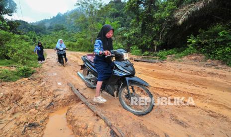 Pelajar melintasi jalan rusak menuju sekolah mereka di Desa Meribung, Limun, Sarolangun, Jambi, Kamis (18/11/2021). Sejumlah pelajar dan warga Desa Meribung yang merupakan desa terpencil di kabupaten itu terpaksa melintasi jalan berlubang dan licin di sejumlah titik sebagai satu-satunya akses jalan darat menuju dan keluar dari desa mereka. 