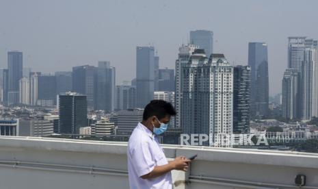 Petugas beraktivitas dengan latar belakang gedung-gedung bertingkat yang diselimuti polusi di Jakarta, Selasa (28/7). Polusi udara kembali menyelimuti langit Jakarta, sejak masa Pembatasan Sosial Berskala Besar (PSBB) memasuki masa transisi. Berdasarkan data AirVisual, kualitas udara Jakarta pada Selasa (28/7) mencapai angka 156 US AQI, yang tergolong tidak sehat. 