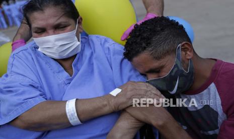 Helena Elvira, 63, menerima pelukan emosional dari putranya setelah sembuh dari COVID-19, saat ia keluar dari rumah sakit lapangan di National Stadium Mane Garrincha, di Brasilia, Brasil, Kamis, 15 Oktober 2020.