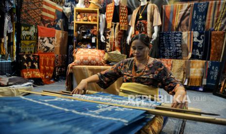 Pengrajin menyelesaikan pembuatan kain tenun pada gelaran International Handicraft Trade Fair (Inacraft) on October 2023 di Jakarta Convention Center, Jakarta, Sabtu (7/10/2023). 