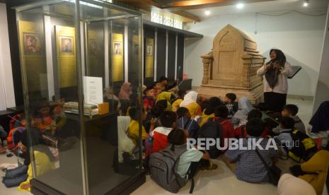 Seorang guru memberikan penjelasan kepada muridnya tentang koleksi benda sejarah dan budaya dalam kegiatan bimbingan belajar (Bimbel) dan edukasi wisata saat berkunjung  di Museum Aceh, Banda Aceh, Ahad (11/9/2022). Petugas Museum Aceh, menyatakan jumlah kunjungan ke Museum Aceh tersebut, mulai meningkat dan setiap hari antara 50 hingga 100 pengunjung termasuk dari kalangan pelajar. 